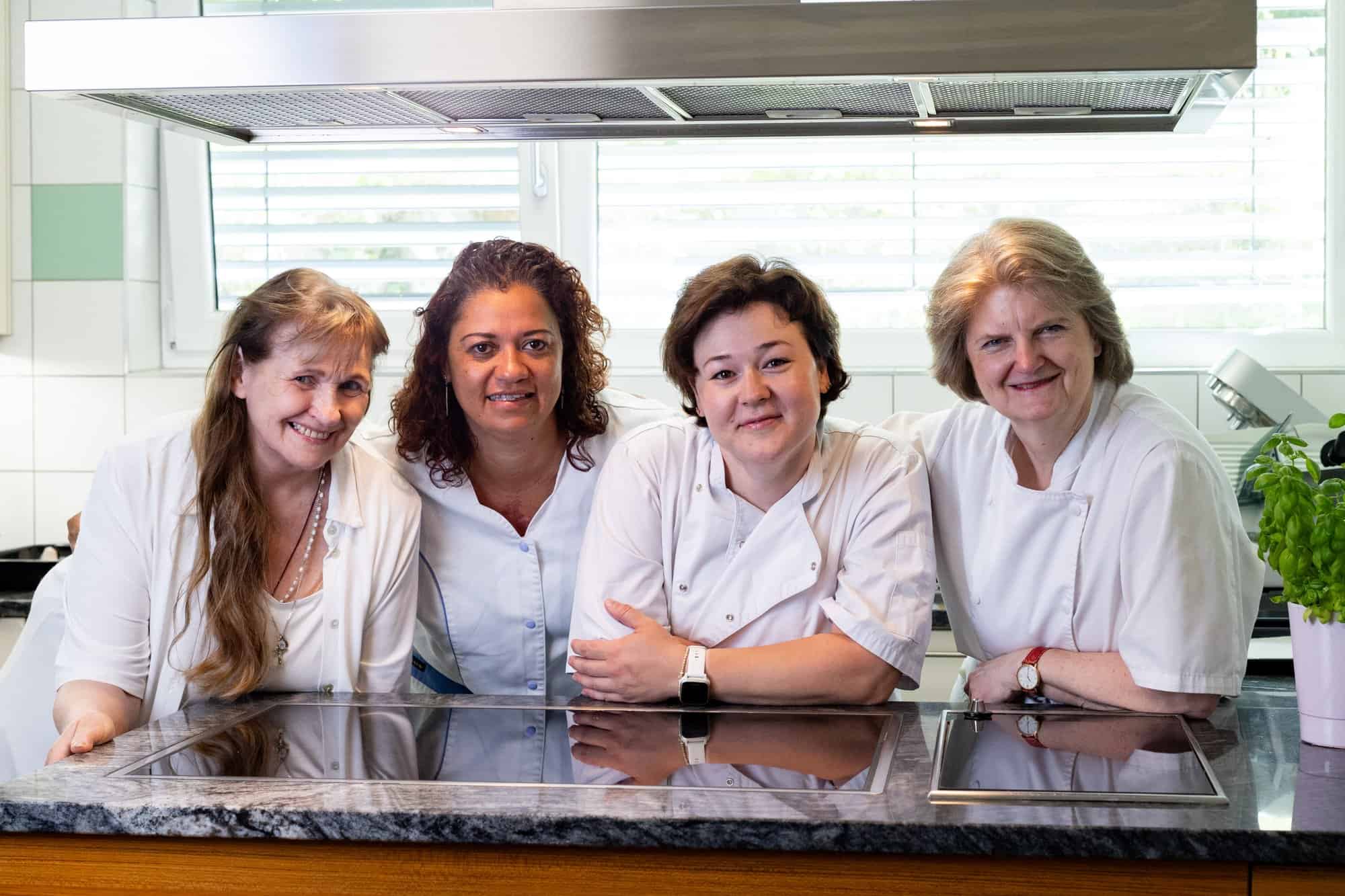 Vier Frauen in Kochschürzen im Küchenbereich des Studentenhauses Sillgraben.