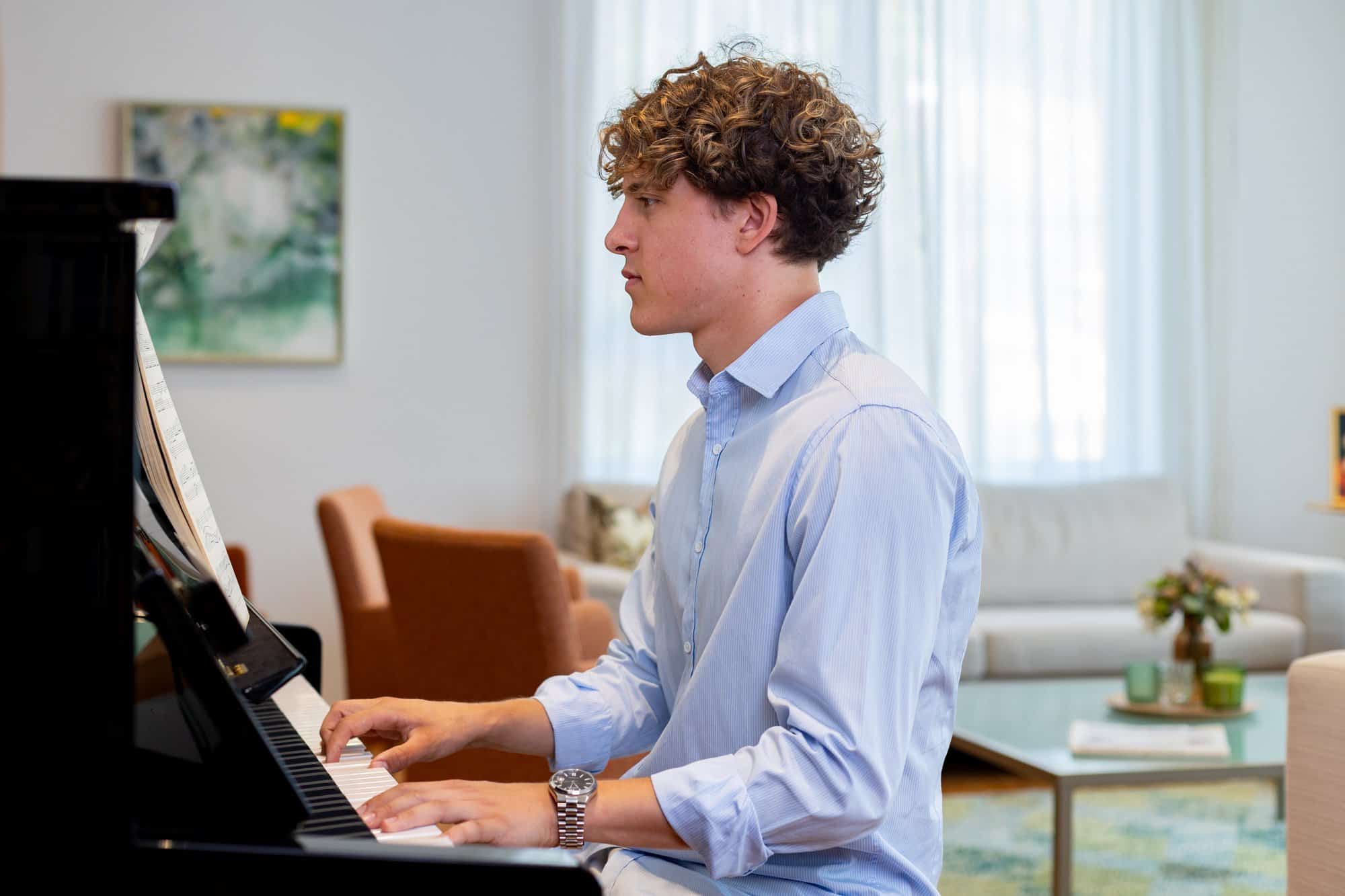 Junge Person spielt Klavier im modernen Gemeinschaftsraum.