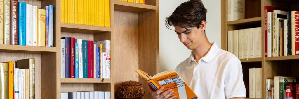 Student liest Buch in der Bibliothek des Studentenheims